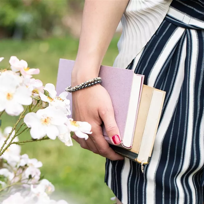 Frau mit Büchern in Rosengarten Frau mit Büchern in Rosengarten